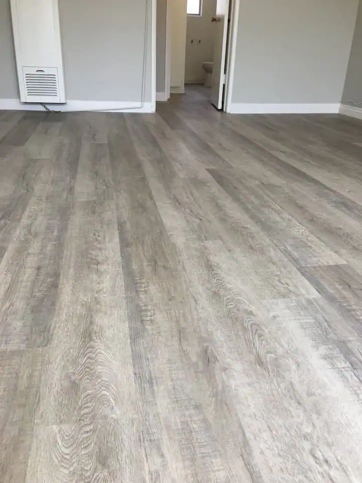 Grey luxury vinyl plank flooring installation featuring sleek modern planks, realistic wood texture, precise alignment, and a clean contemporary finish.